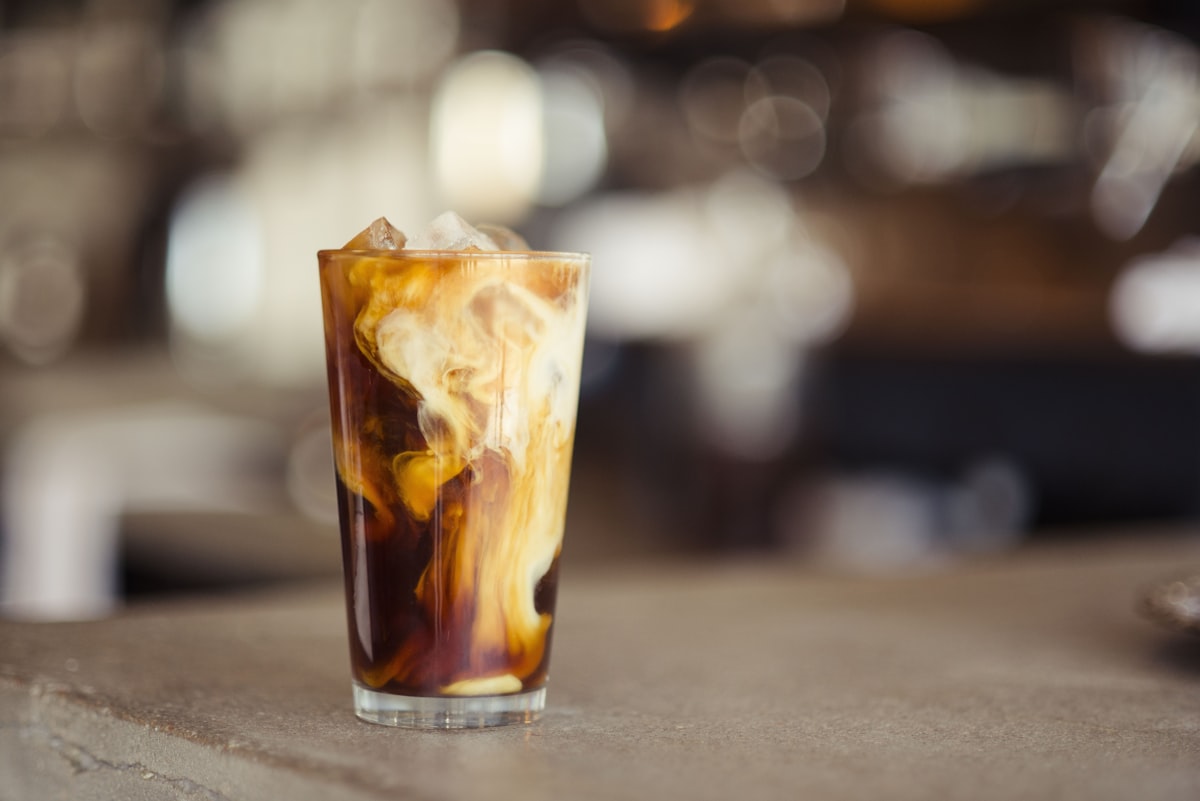 A glass of cold brew coffee with cream swirling through it