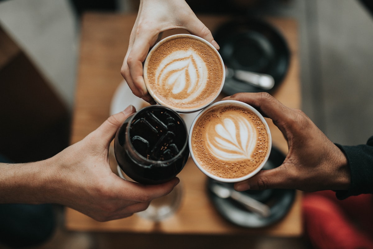 A cup of coffee on a saucer beside scattered beans